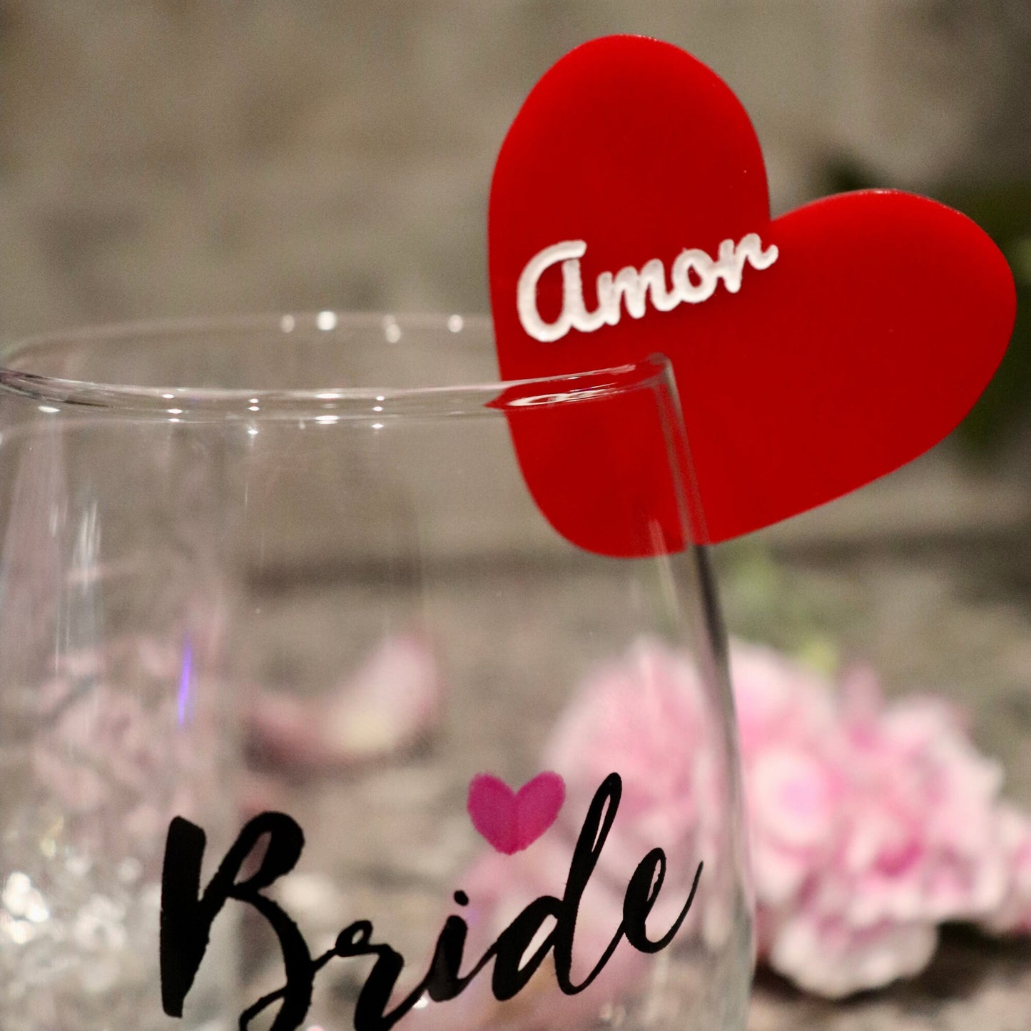 Red acrylic drink tag on wine glass. “Amor” engraved