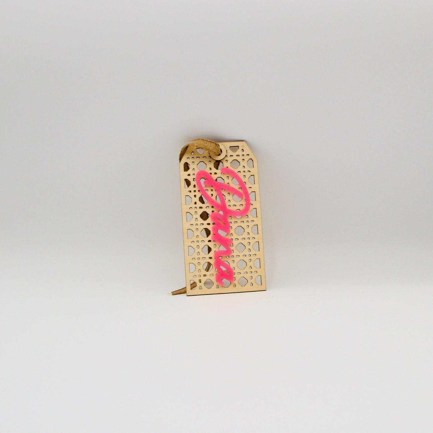 Rattan tag with pink text on a vertical angle