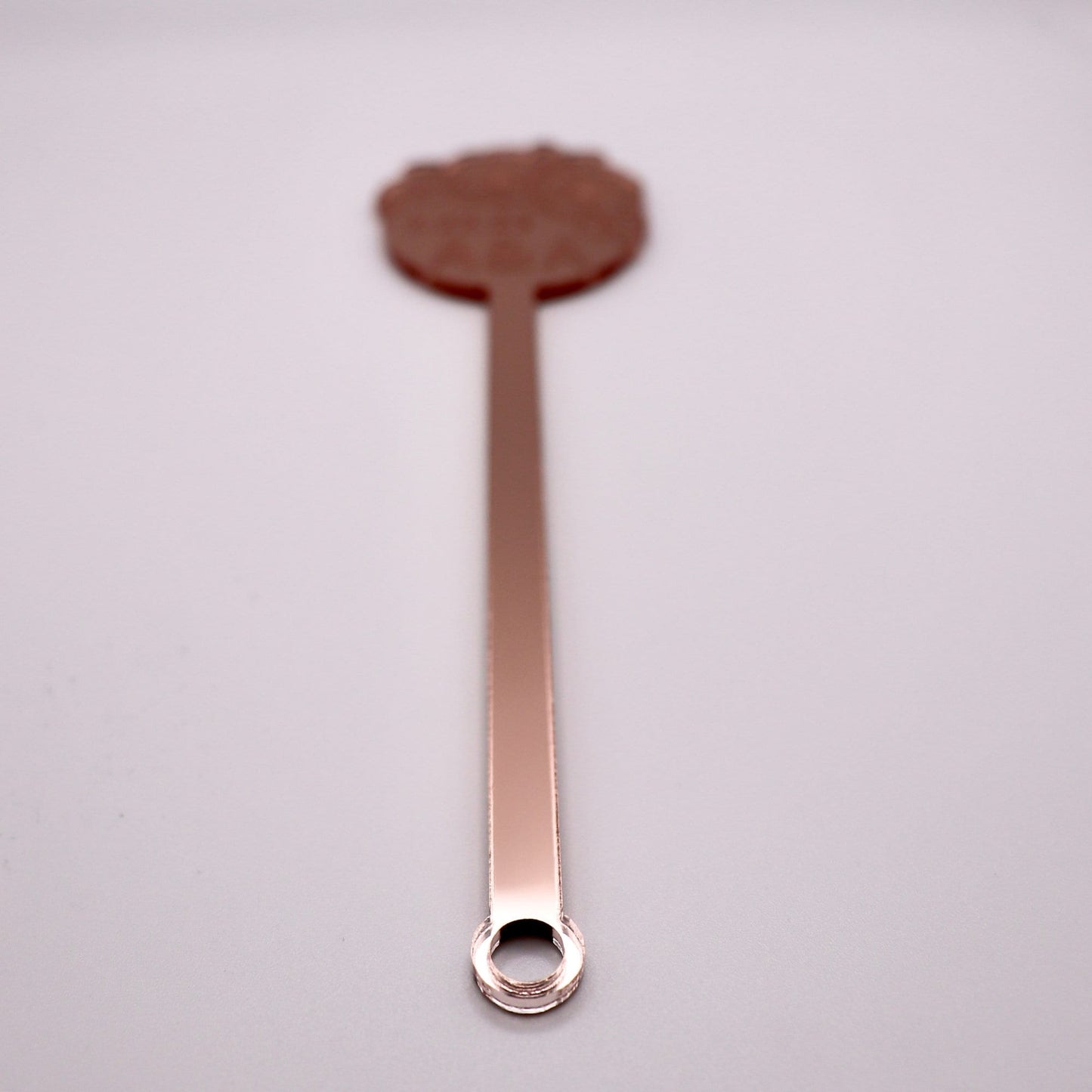 Rose gold mirrored drink stirrer zoomed in to the bottom of it to demonstrate its stirring abilities