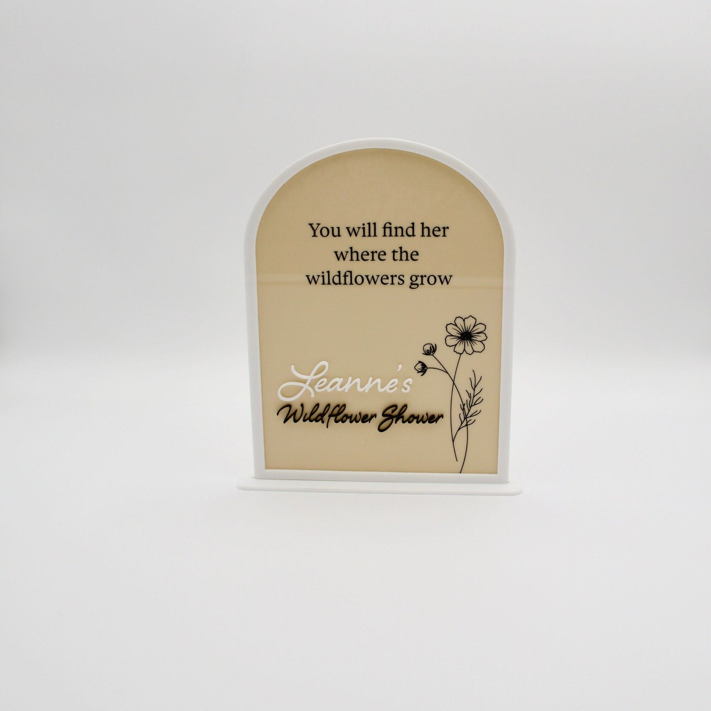 Arched acrylic sign in beige and white with black etched words. Featuring an etched flower on the right.