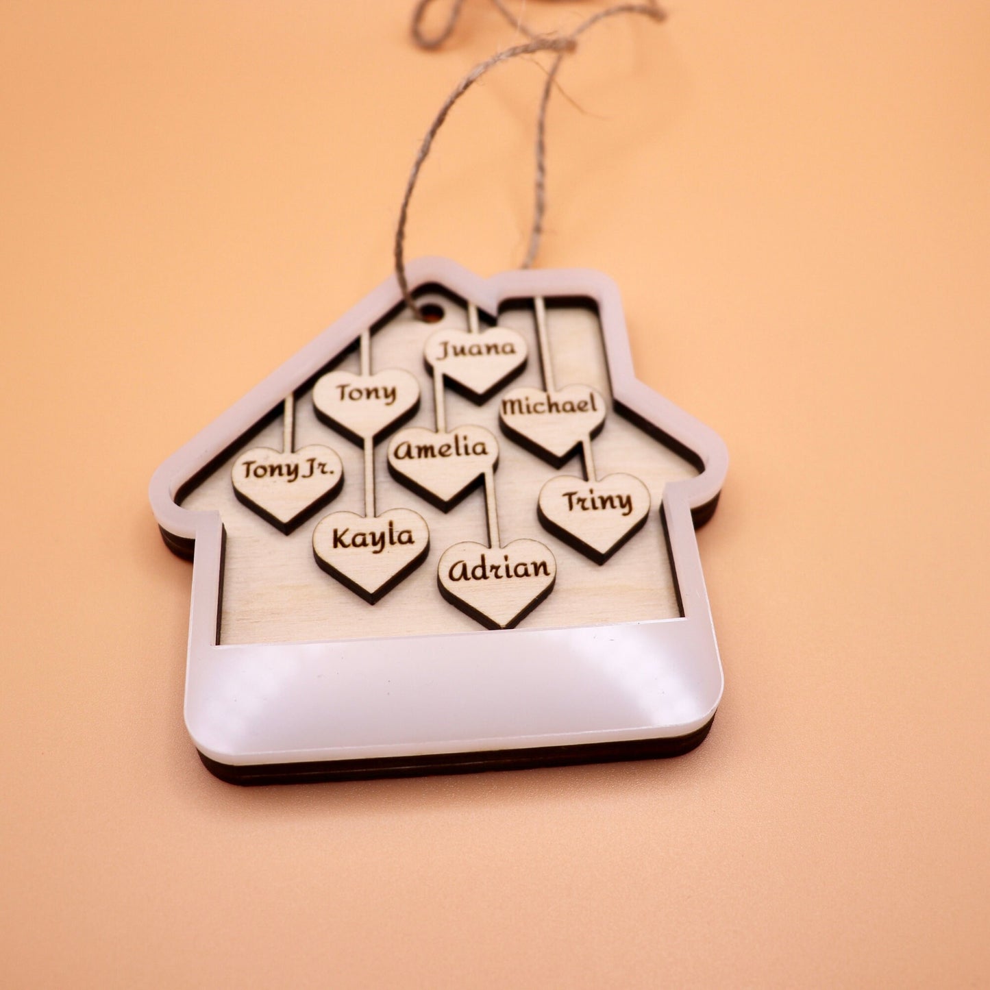 Lying down image of the White acrylic house ornament with 8 custom names on wooden hearts