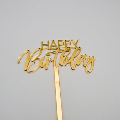 Gold mirrored acrylic cake topper. “happy”is in bold thin letters. “Birthday” is in a cursive font.