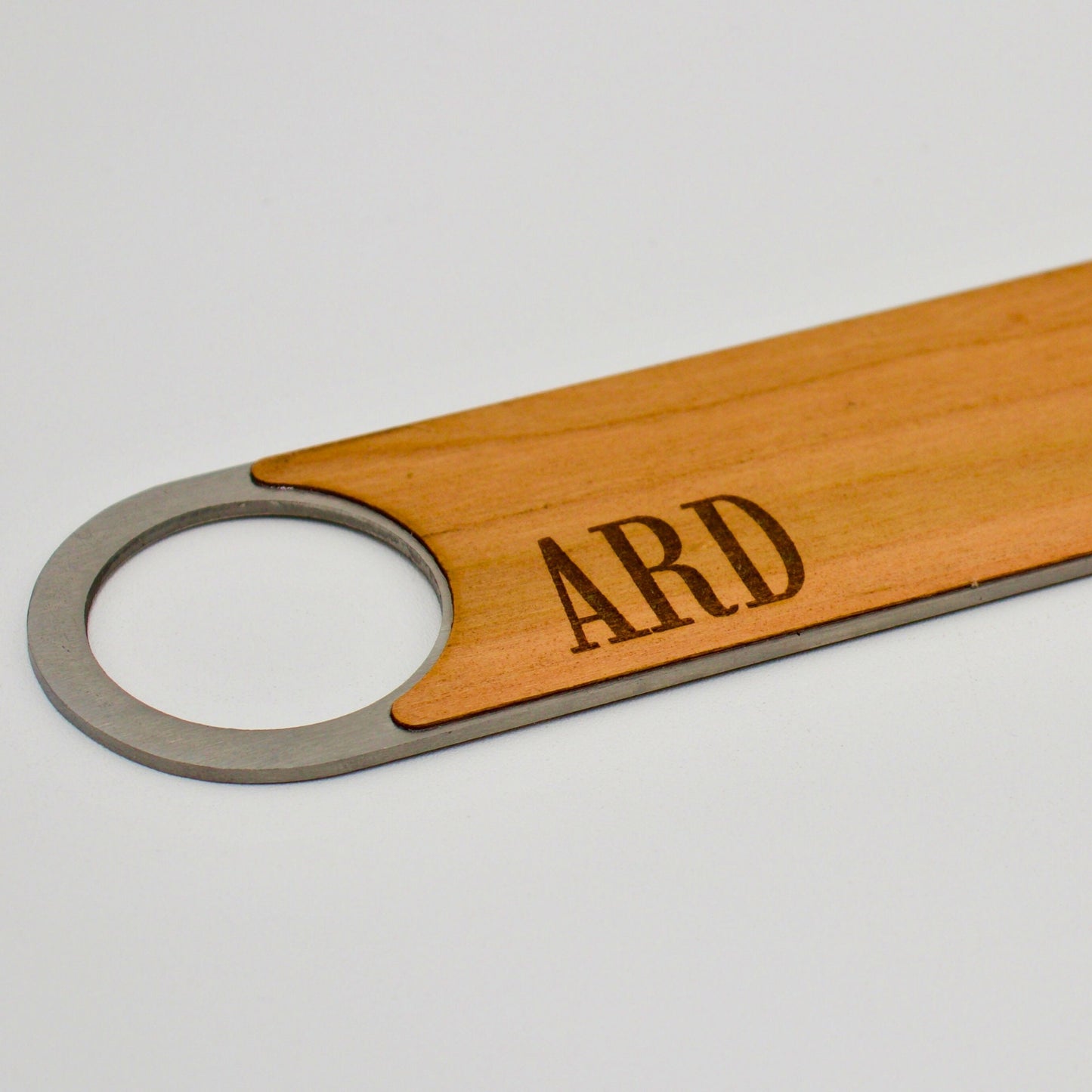 close up of monogram engraved onto wooden bottle opener