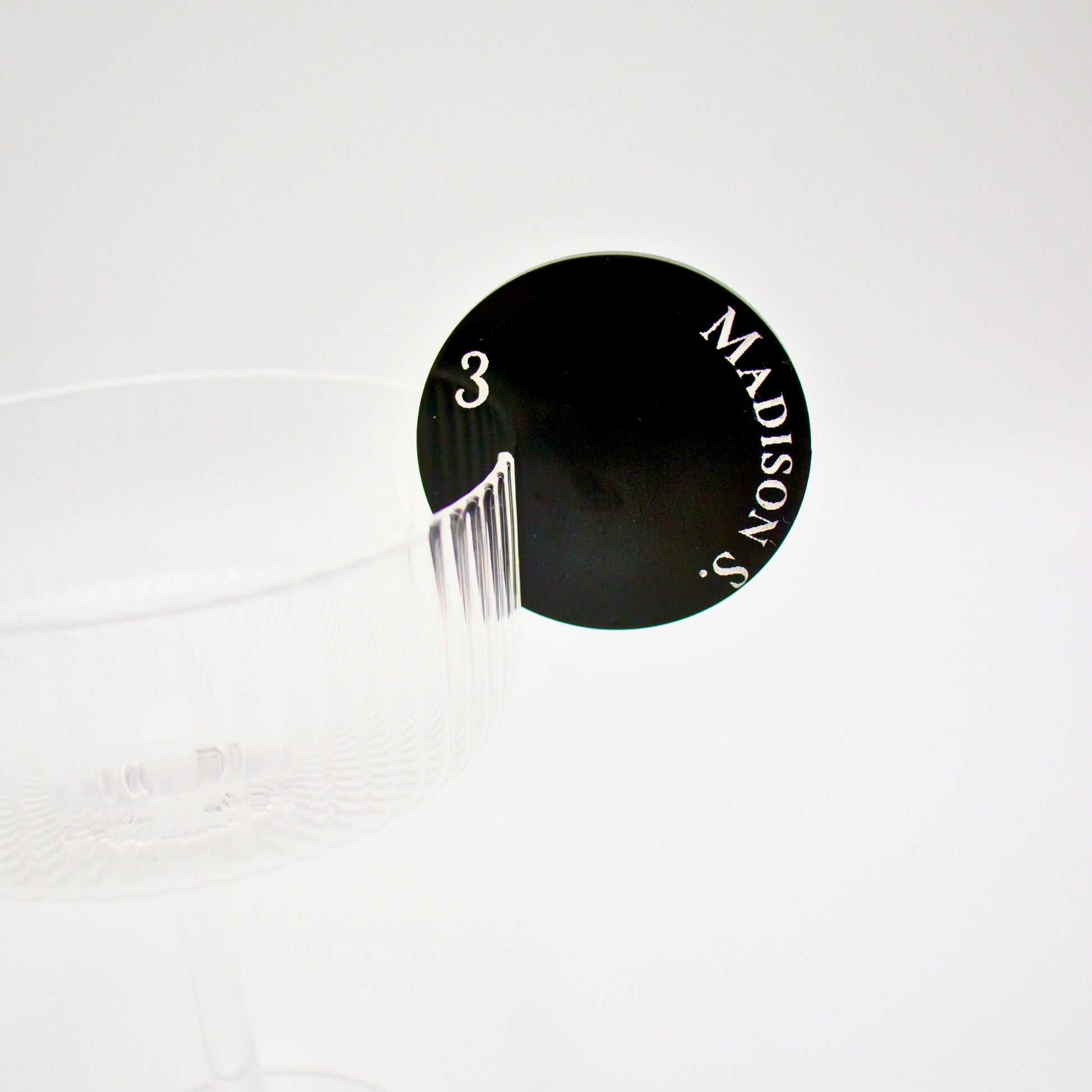 Close up of round drink tag featuring black pearl acrylic