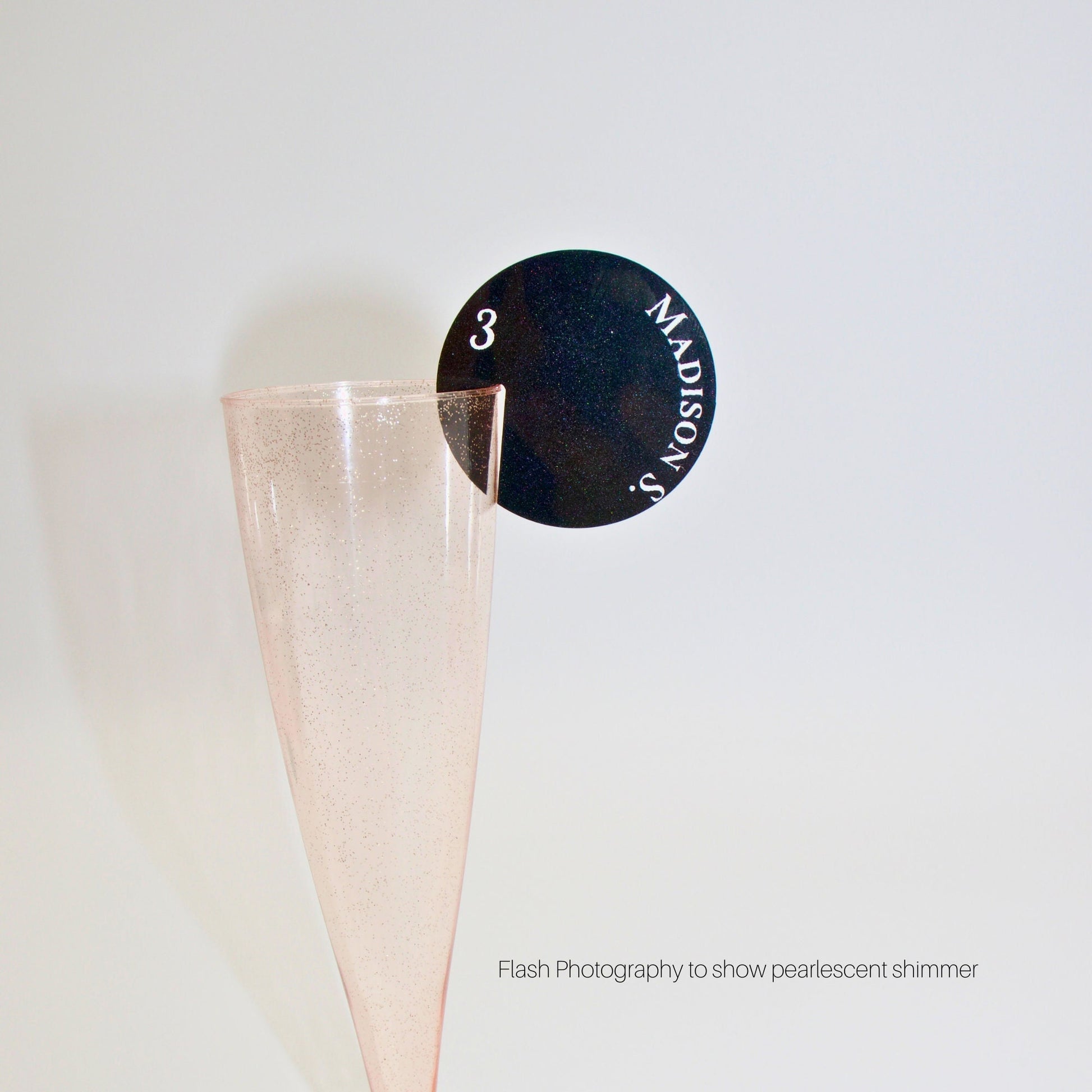 Black pearl round drink tag on a pink champagne glass